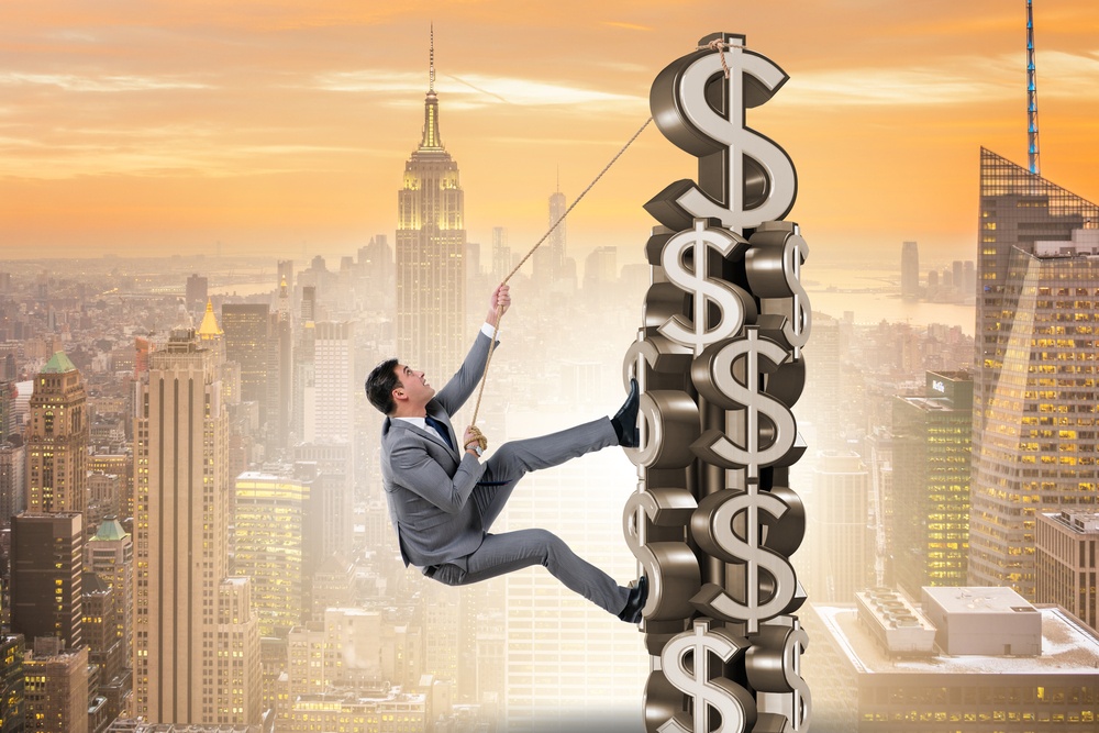 business man climbing money tower.jpg